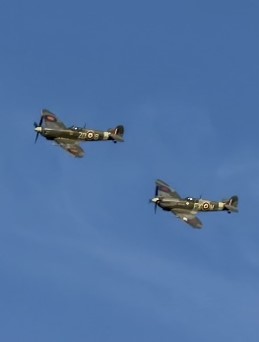 Two vintage military propeller aircraft fly