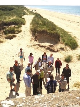 A group of hikers gathers on a sandy coastal trail