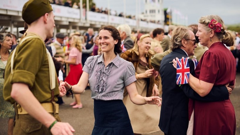 A woman in a gray blouse dances at a busy outdoor gathering