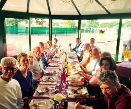 A cheerful group of adults shares a meal around a long tabl